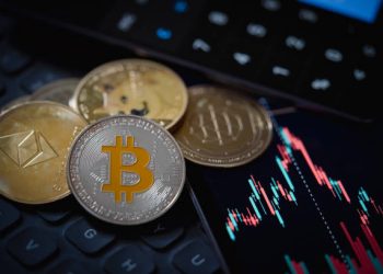 Gold Bitcoin and Ethereum cryptocurrency coins with candle stick graph chart, laptop keyboard, and digital background.